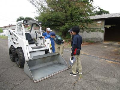 スキットステアローダーの説明を受ける学生達