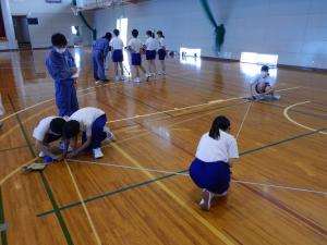 生徒たちが四角形の面積を巻き尺で測定している様子