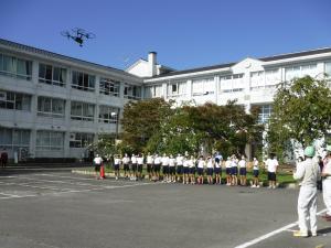 ドローンが空中から生徒たちを撮影している様子